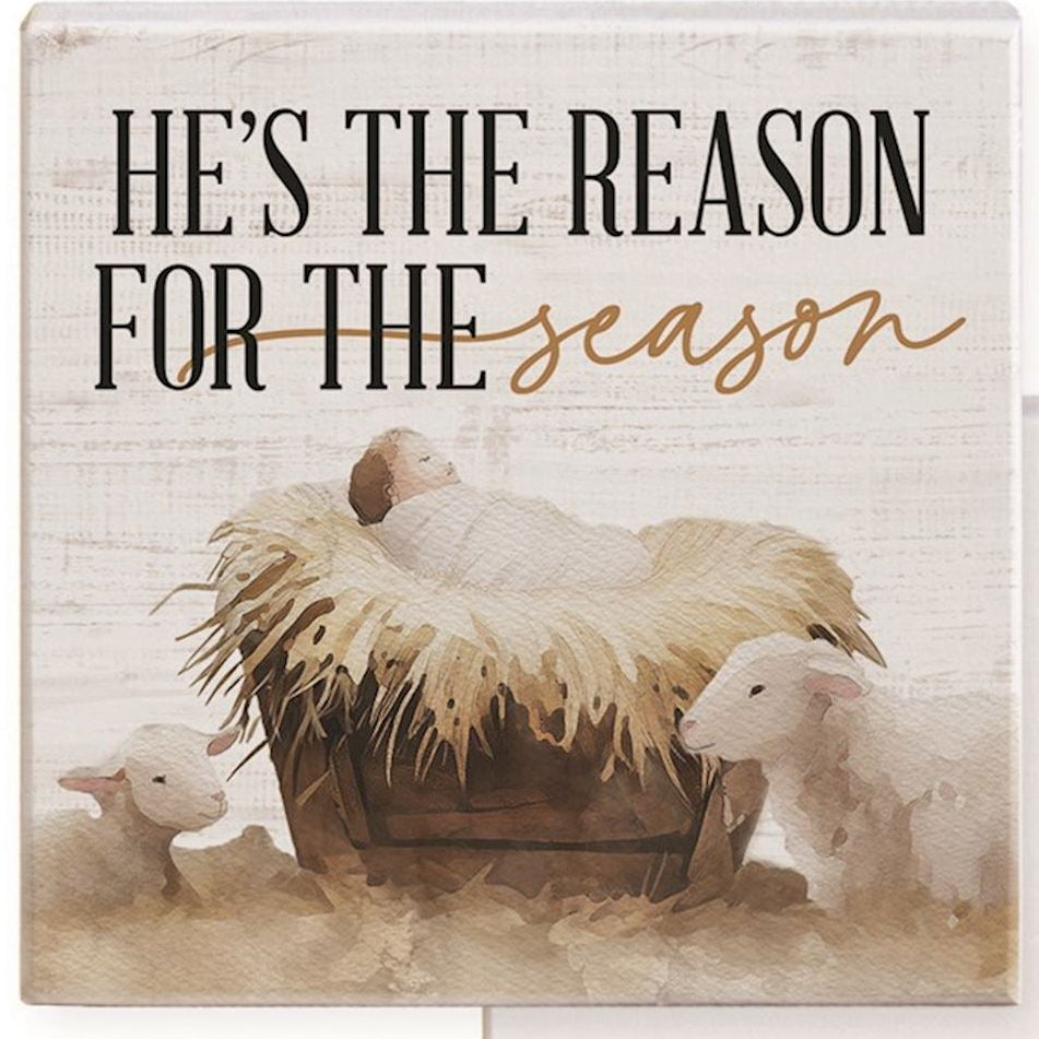 Decorative sign with sheep and hay bale, featuring text 'He's the Reason for the Season', on a white background.